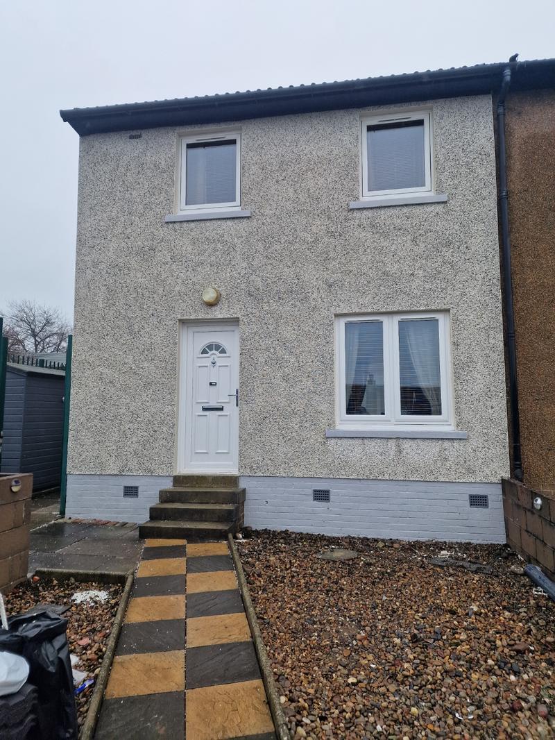 The same house finished in fresh grey harling with a painted base course