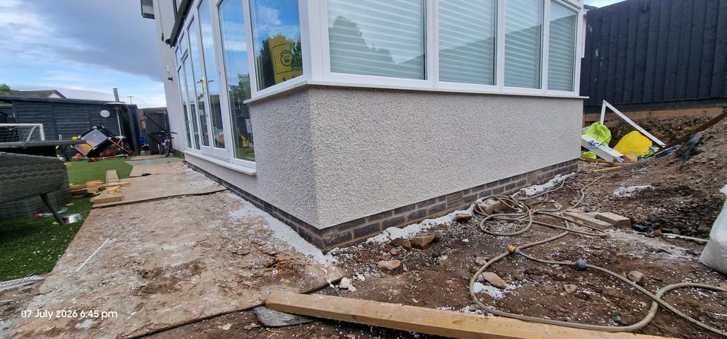 New dry dash above a dark brick plinth on an extension