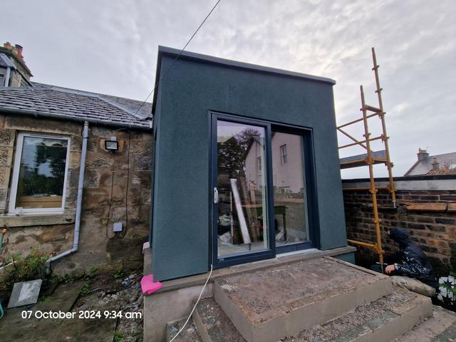 Smooth render in dark teal on a garden-room extension
