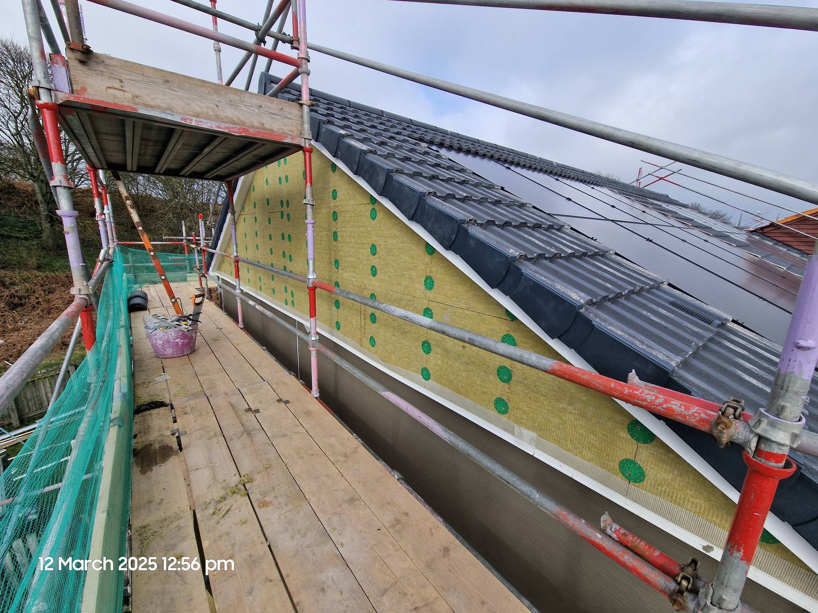 Wall insulation, a new roof and an in-roof solar array on one property, photographed from the scaffold