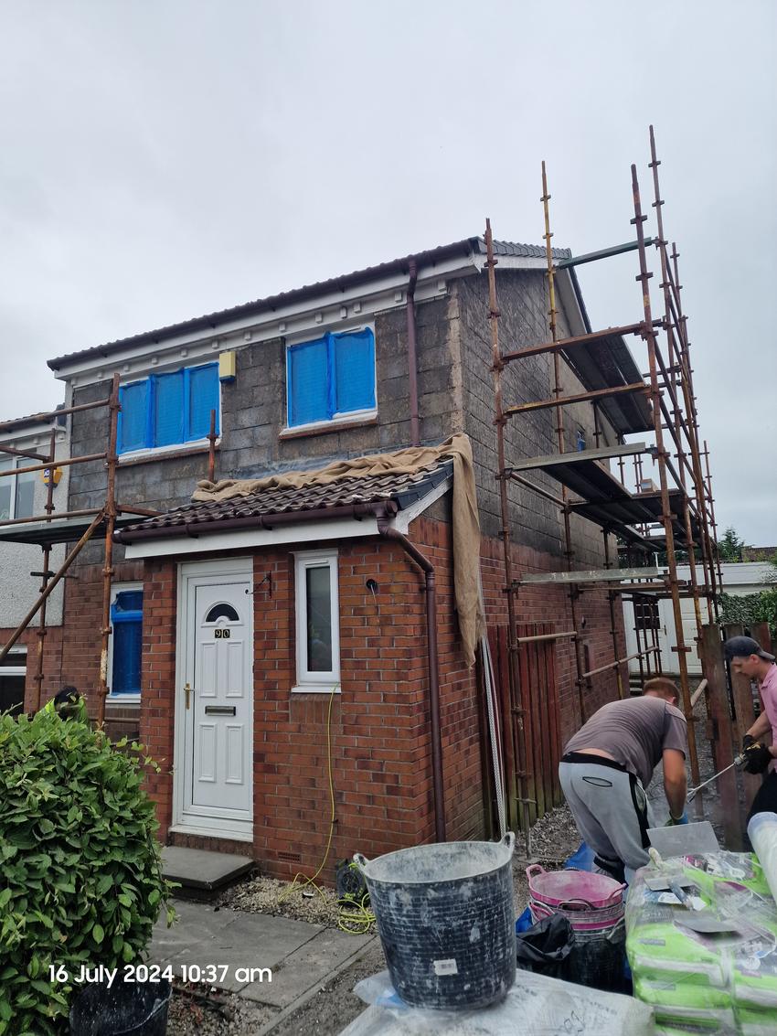 Front elevation stripped, windows masked, team working from the scaffold
